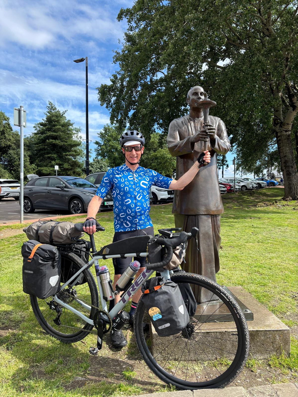 Welsh Pilgrimage to the 7 Sri Chinmoy Peace Staures - a photo of Rasmivan with his bicycle standing next to one of the peace statues